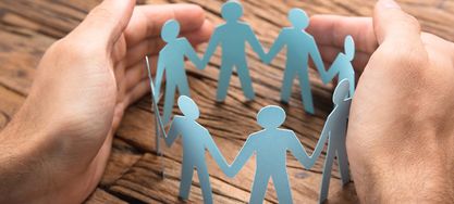 2 Hände halten mehrere ausgeschnittene Figuren zusammen 