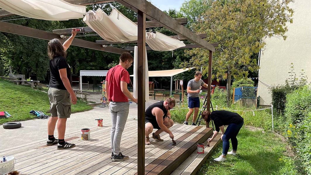 Team die gemeinsam einen Holzboden streichen