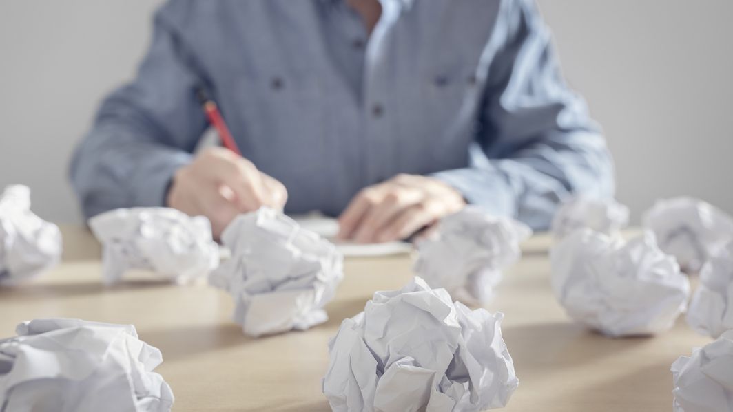 Person blickt auf viele zerknüllte Papierzettel