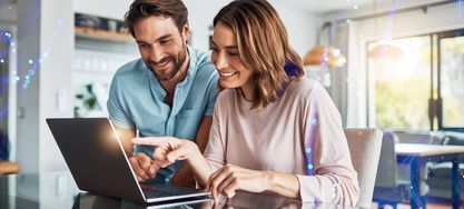 Ein Mann und eine Frau die vor einem Laptop in einem hellen Raum sitzen