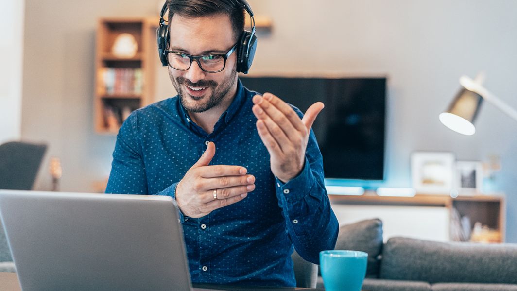 Gestikulierender Mann vor seinem Laptop im Home-Office