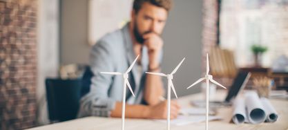 Mann blickt auf mehrere Windräder auf einem Schreibtisch 