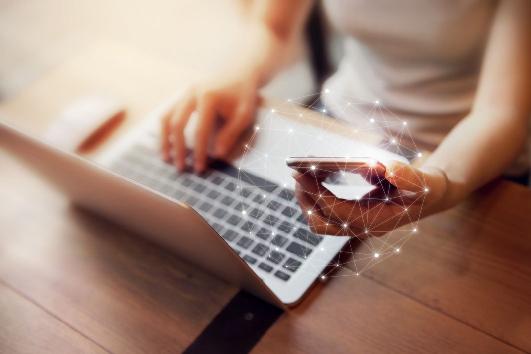 Wer ist die Generation Z? Person, die am Laptop sitzt und Handy in der Hand hält