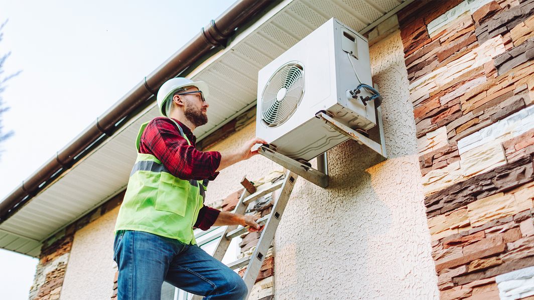 Mann prüft eine Wärmepumpe am Haus