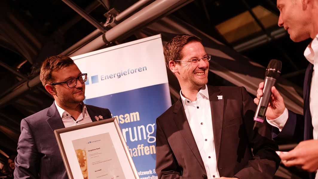 Energieforen-Award-Verleihung Zwei Personen verleihen einen Preis an eine dritte Person auf einer Bühne