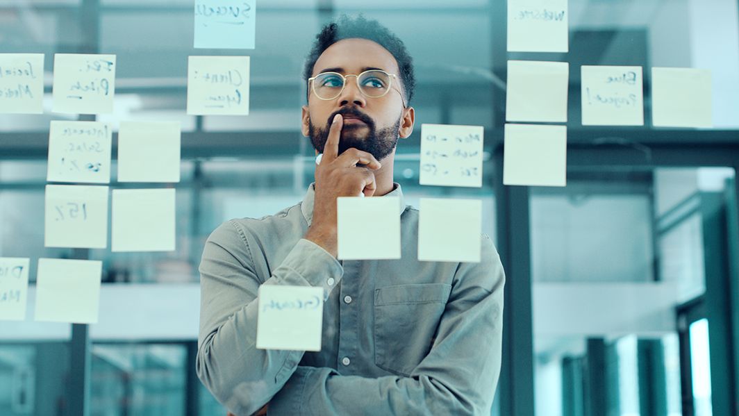 Entwicklung neuer Geschäftsfelder Ein Mann steht vor einer Glasscheibe mit Post-its und denkt nach