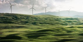 Eine grüne Landschaft auf dem Windräder zu sehen sind
