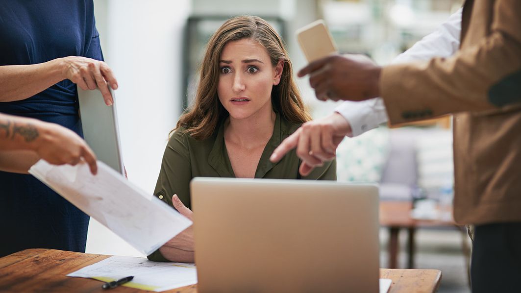 Status quo und Chancen des Forderungsmanagements Mehrere Finger zeigen auf eine Frau, die vor einem Laptop sitzt.