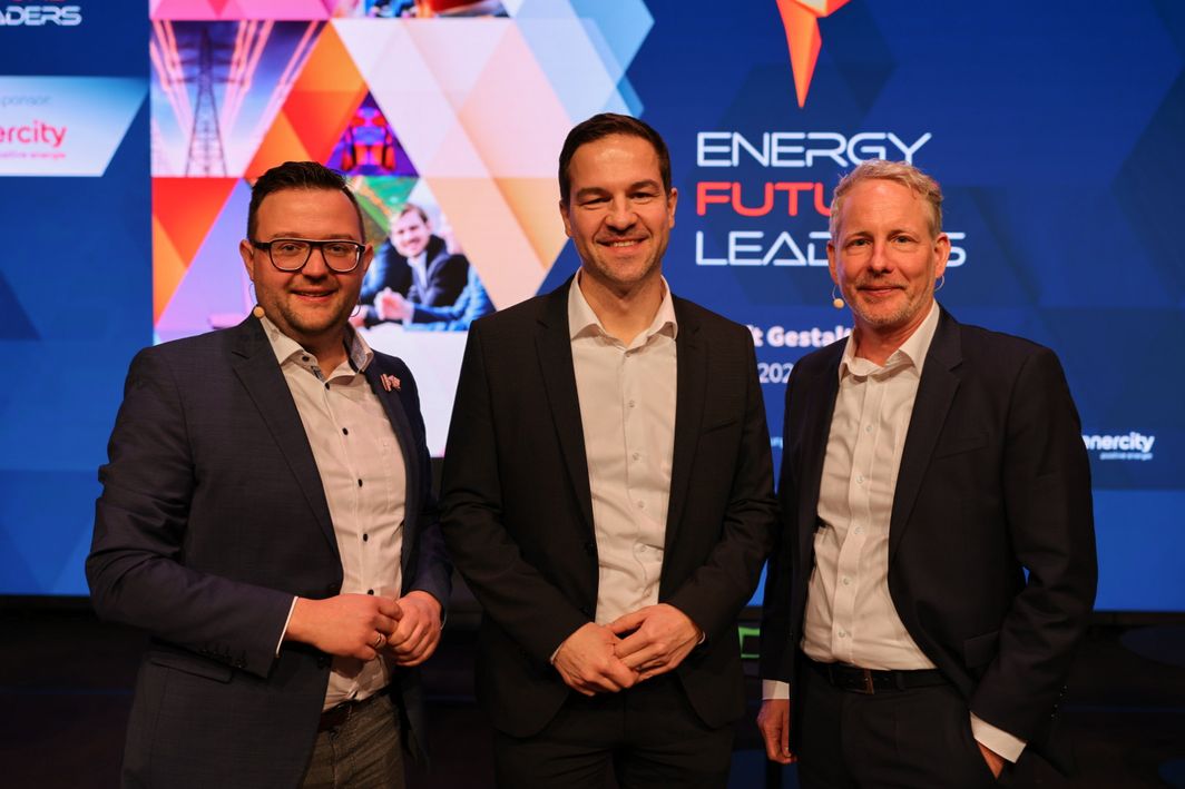 Drei Herren die nebeneinander stehen und in die Kamera lächeln