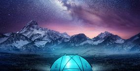 Ein Zelt in den Bergen unter einem eindrucksvollen Sternenhimmel.
