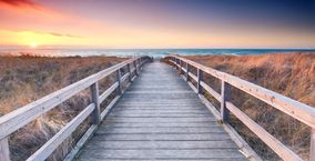 Holzsteg am Strand. Im Horizont das Meer 