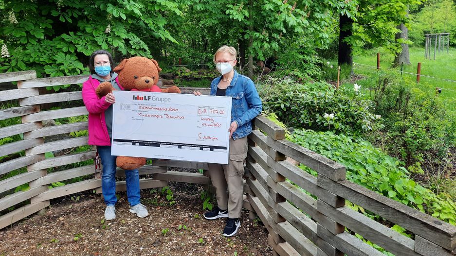 Spendenübergabe Zwei Menschen halten einen Scheck in der Hand