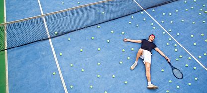 Mann liegt geschlagen auf dem Tennisplatz 