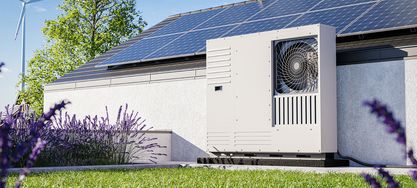 Wärmepumpe neben einem Haus mit Solaranlage auf dem Dach