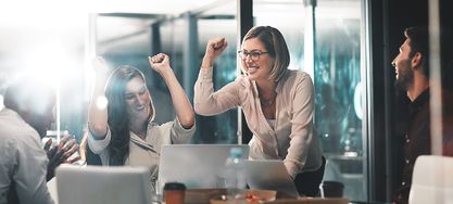 Vier Kolleginnen und Kollegen in einem Büro freue sich über den erfolgreich erstellten VSME-Bericht für ihr Unternehmen.